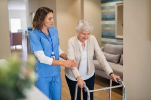 Adult daughter chatting with an elderly woman in a bright assisted living common room with natural light.