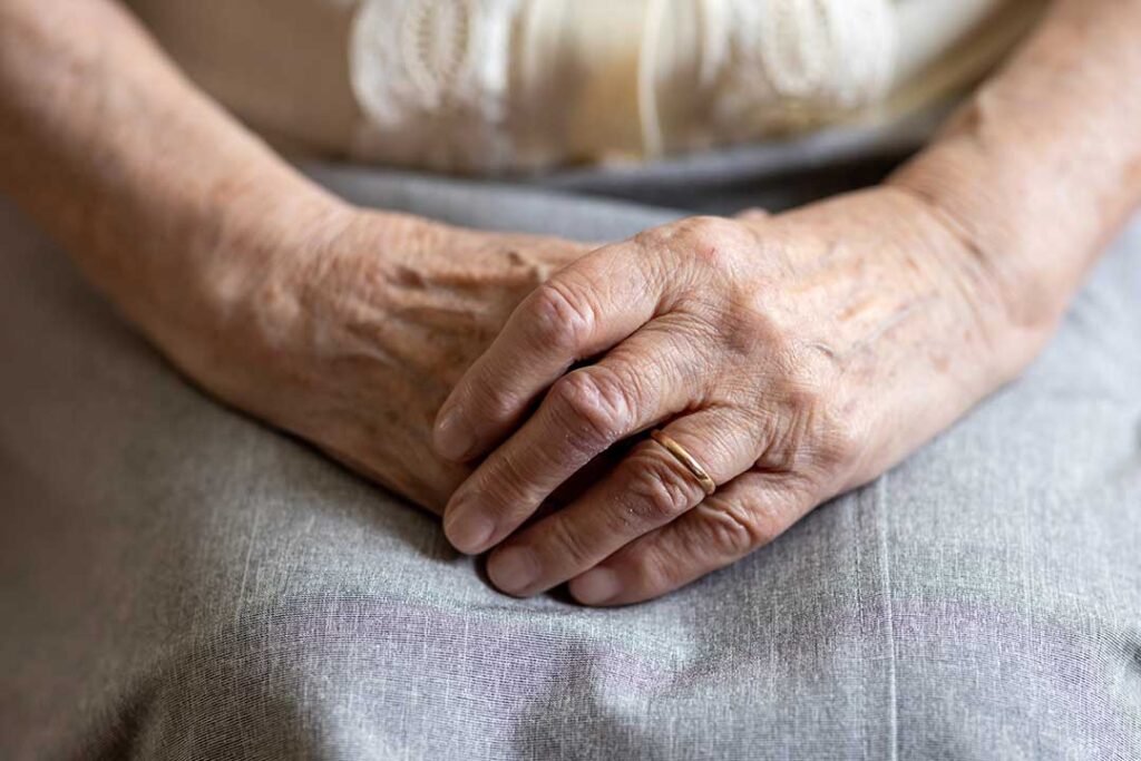 Older adult choosing clothing while a caregiver offers respectful assistance in a bright private room.